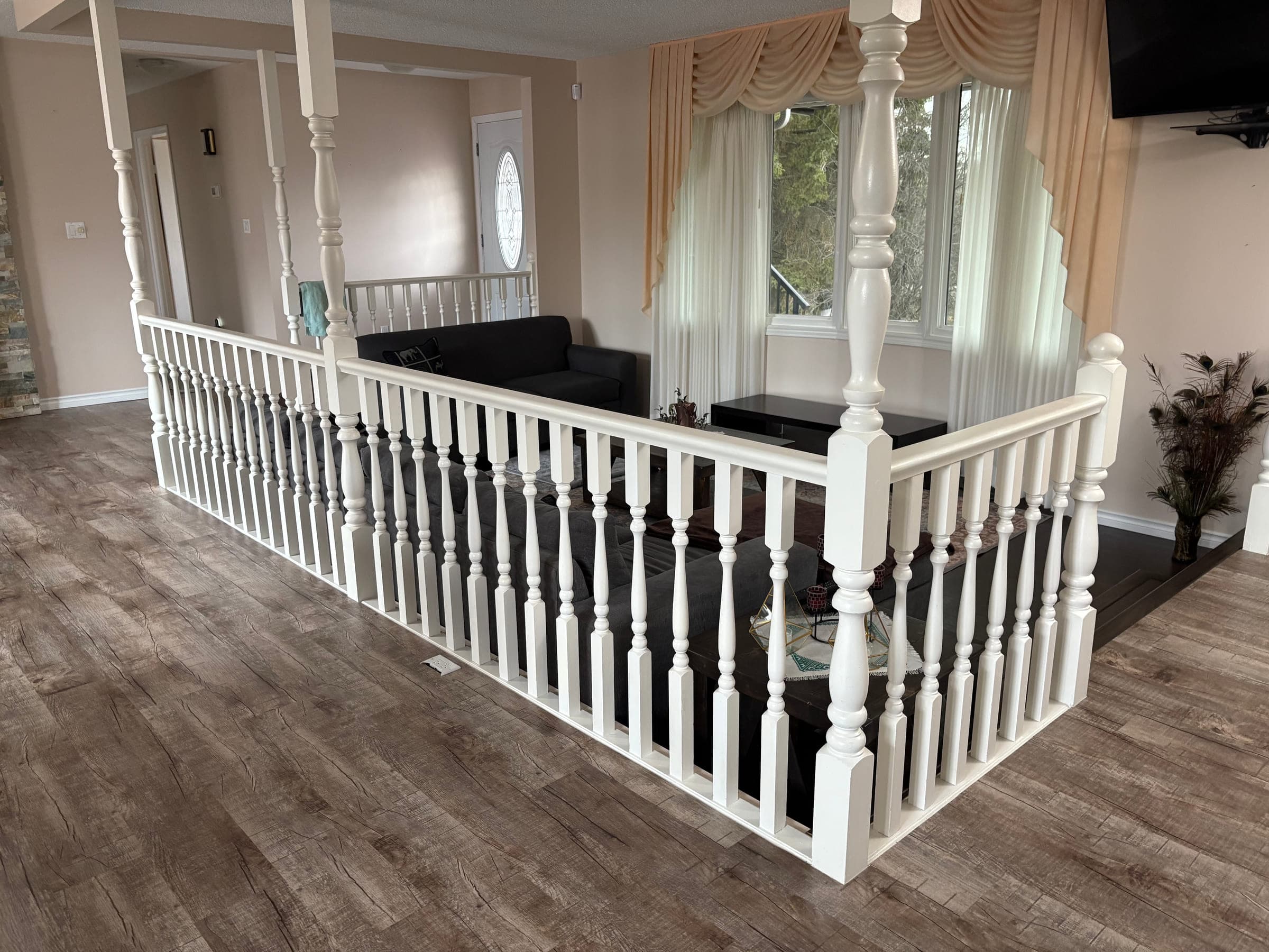 White painted spindle railing and newel posts overlooking a living room
