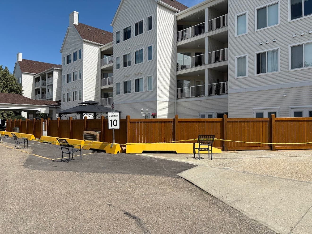 Newly stained wood privacy fence along the parking area of a multi-unit residential building