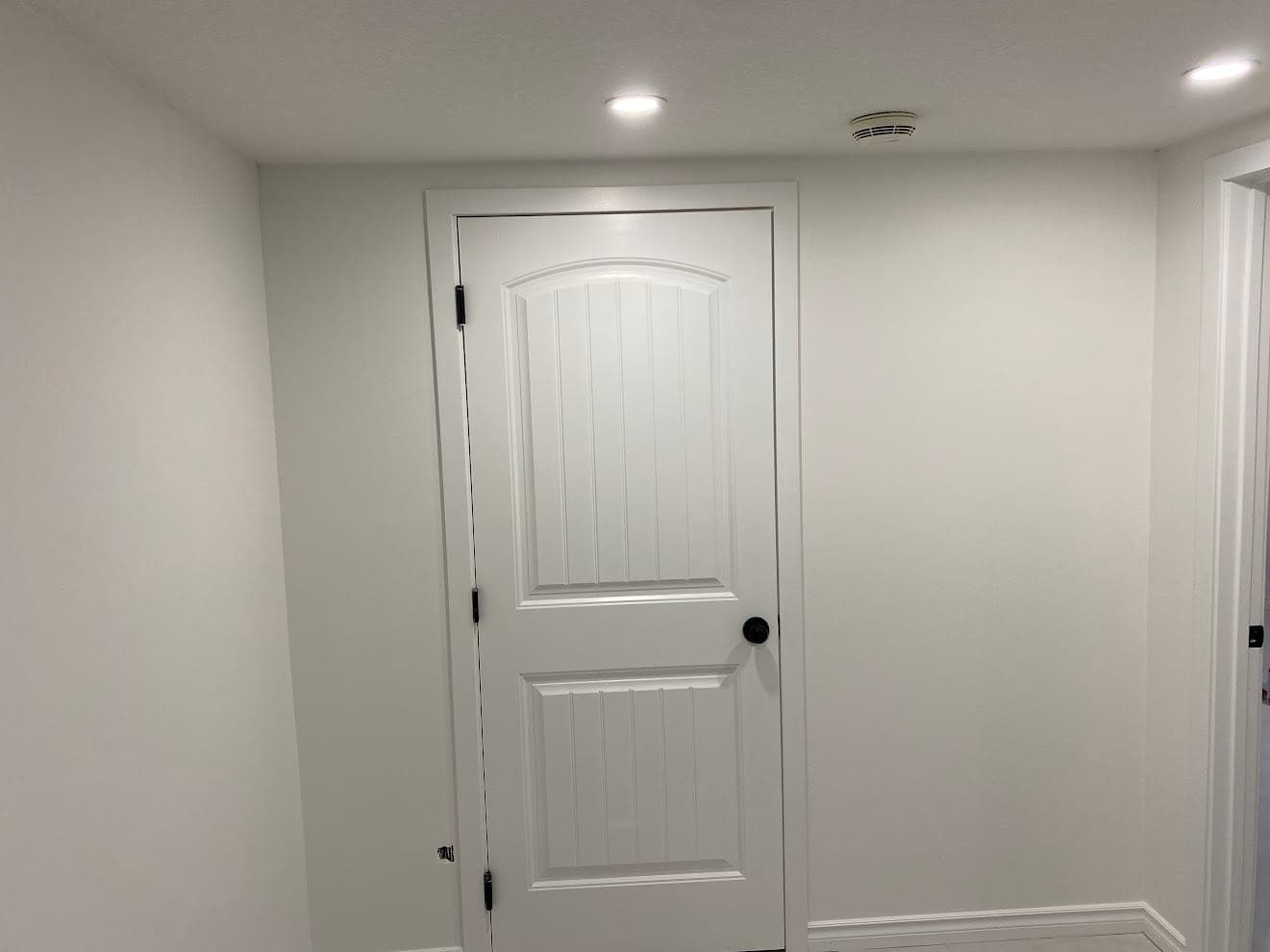 Freshly painted white interior door, casing and baseboard against a clean white wall