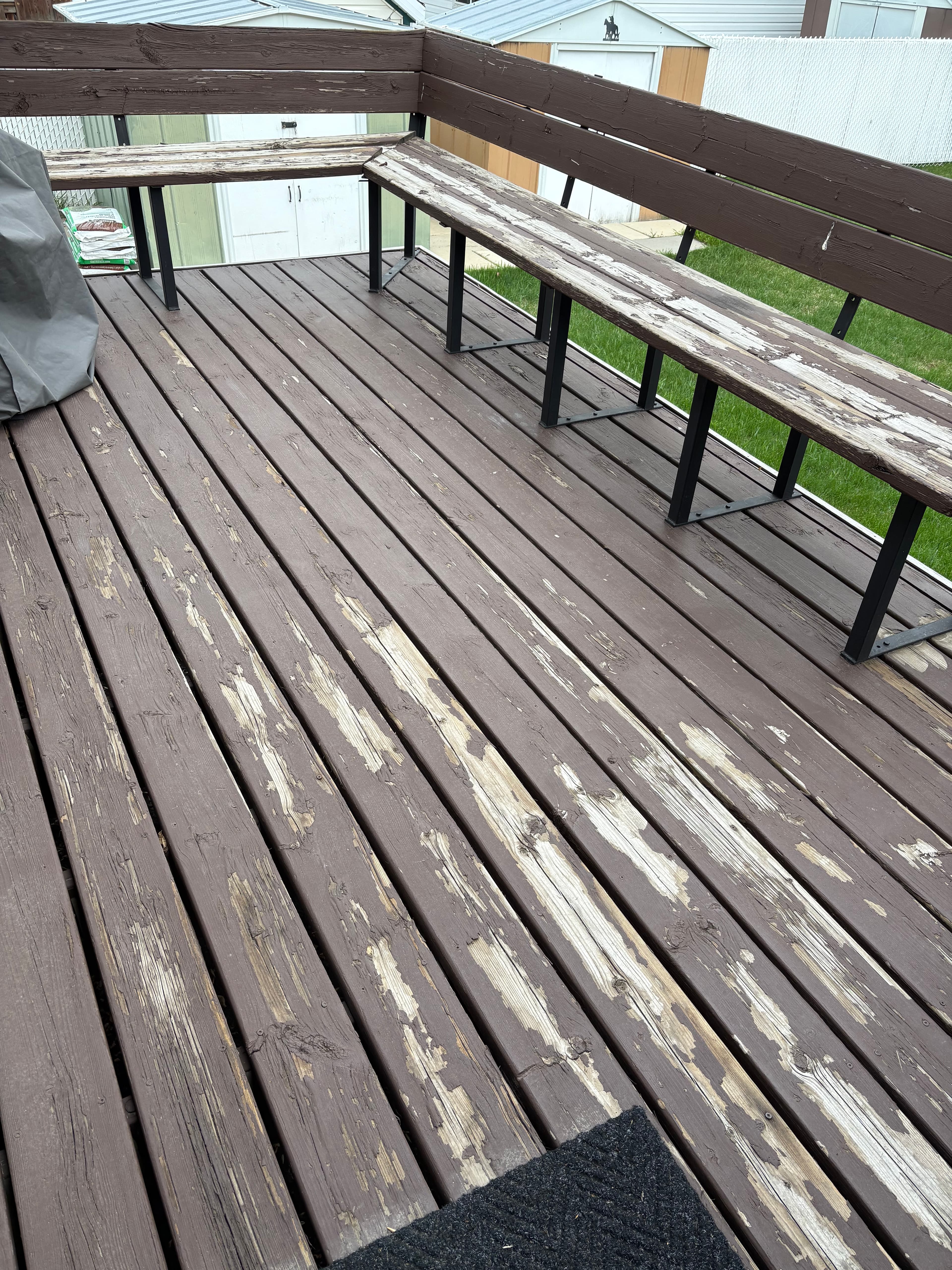 Deck boards and bench seating with failing stain before prep